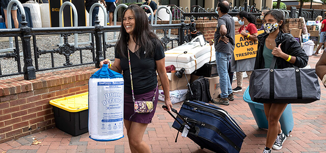 Students moving into the dorms carrying luggage