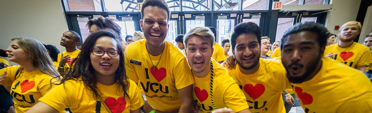 Group of students smiling wearing gold i love vcu shirts